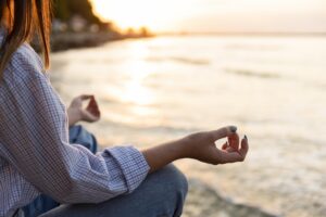 mujer-meditando-en-la-playa-con-espacio-de-copia